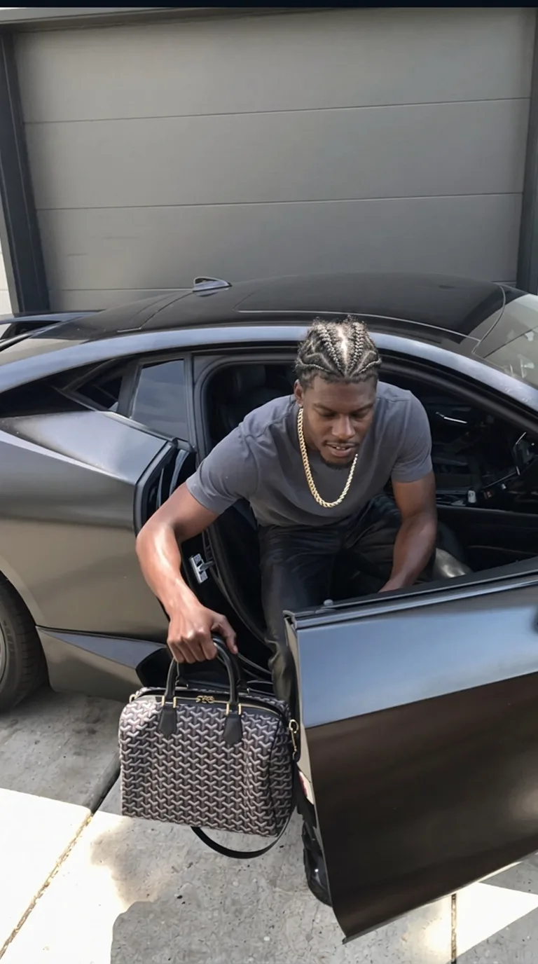 A person in casual attire is getting out of a car, holding a patterned handbag.