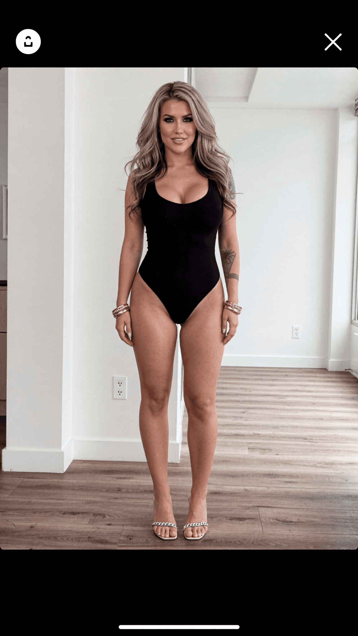 A woman in a black swimsuit poses confidently in a studio setting.
