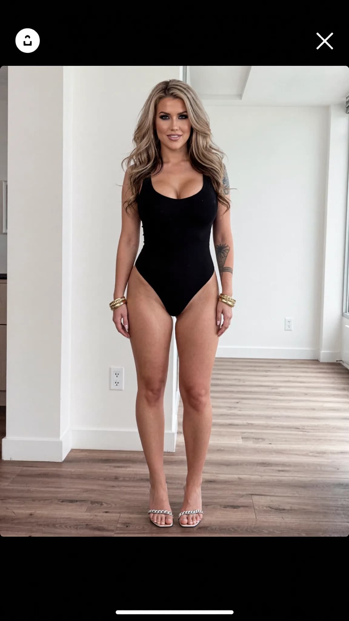 A woman in a black swimsuit poses confidently in a studio setting.