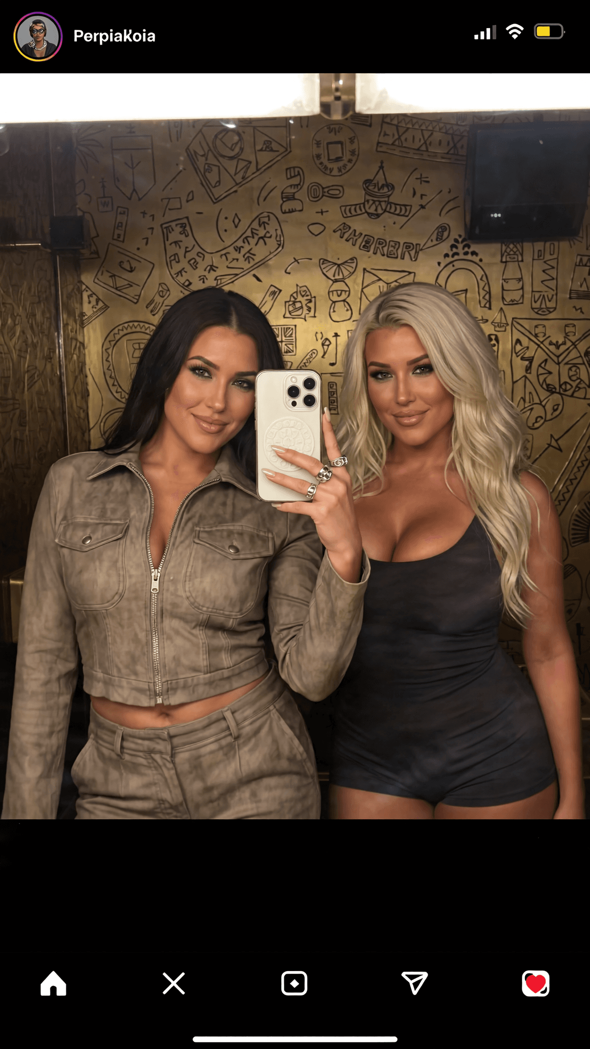 Two women pose for a mirror selfie in casual athletic wear.