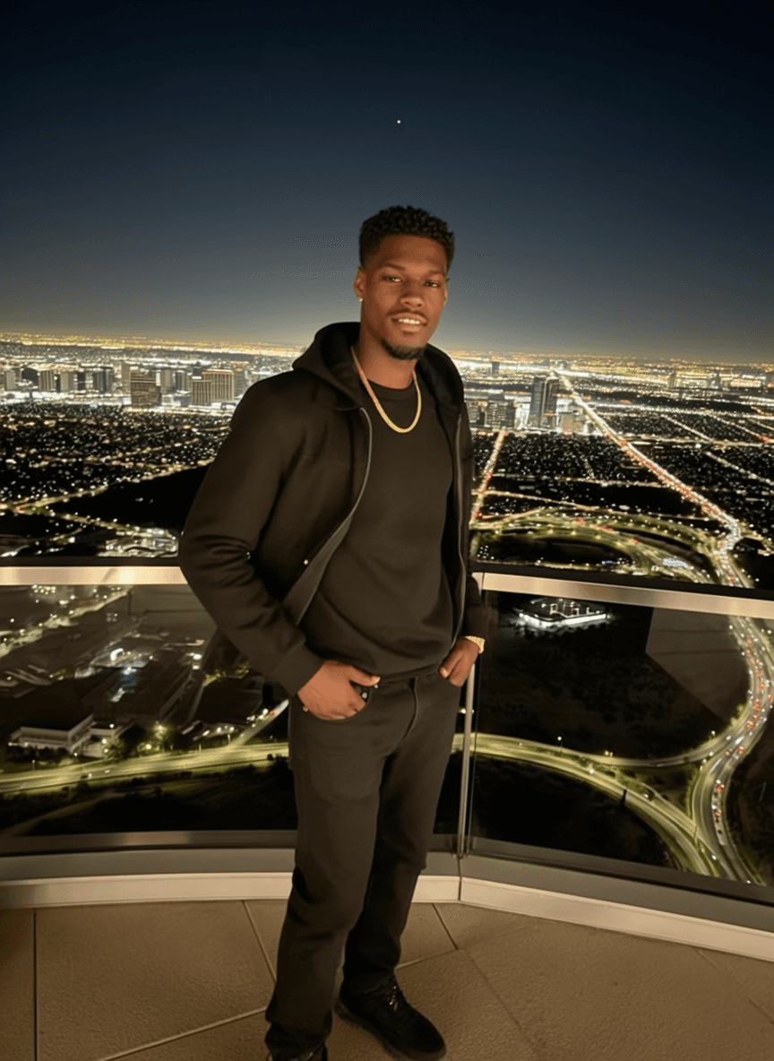 A person stands on a balcony at night, overlooking a cityscape.