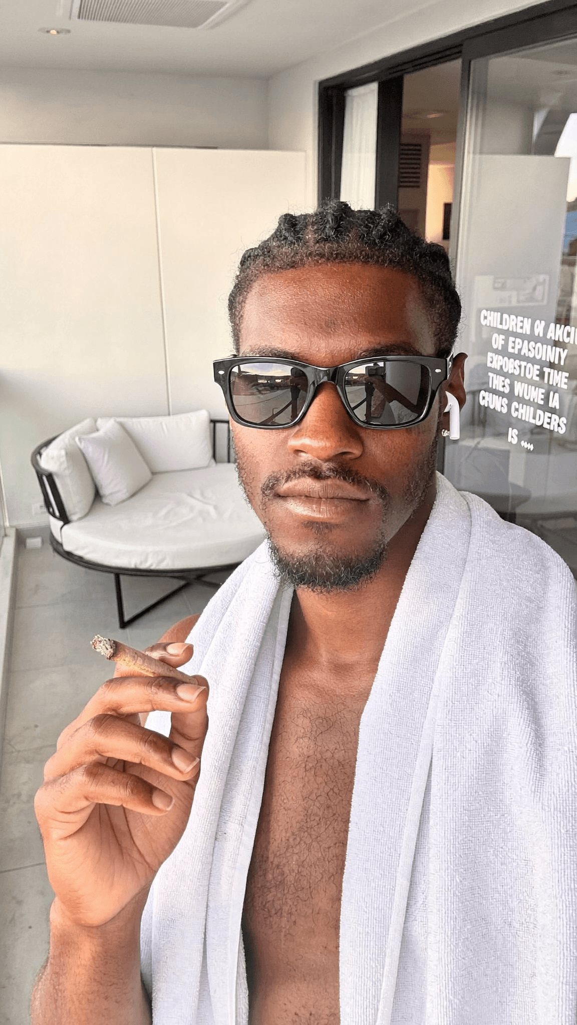 A person wearing a robe is holding a cigar on a balcony.