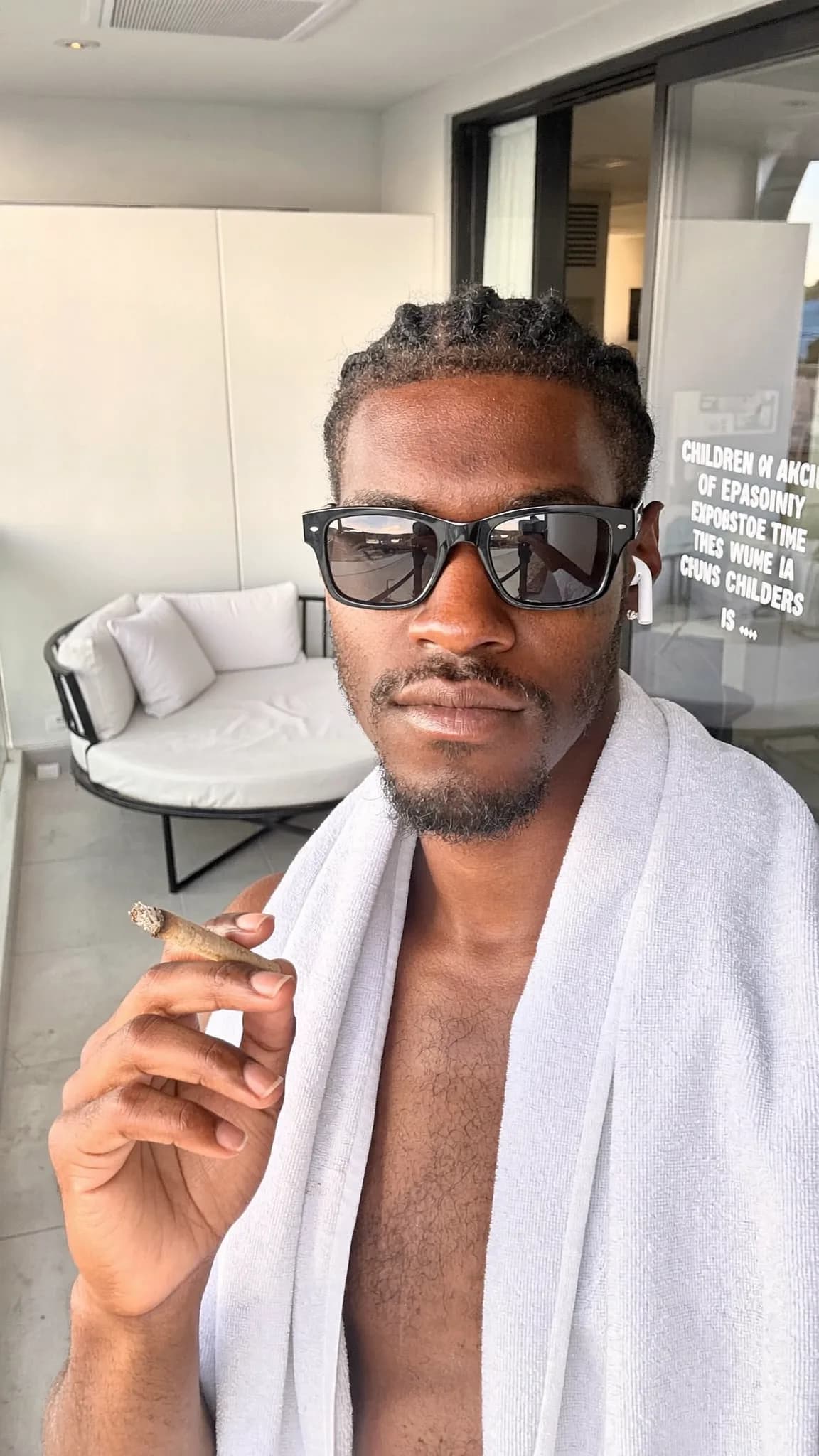 A person wearing a robe is holding a cigar on a balcony.