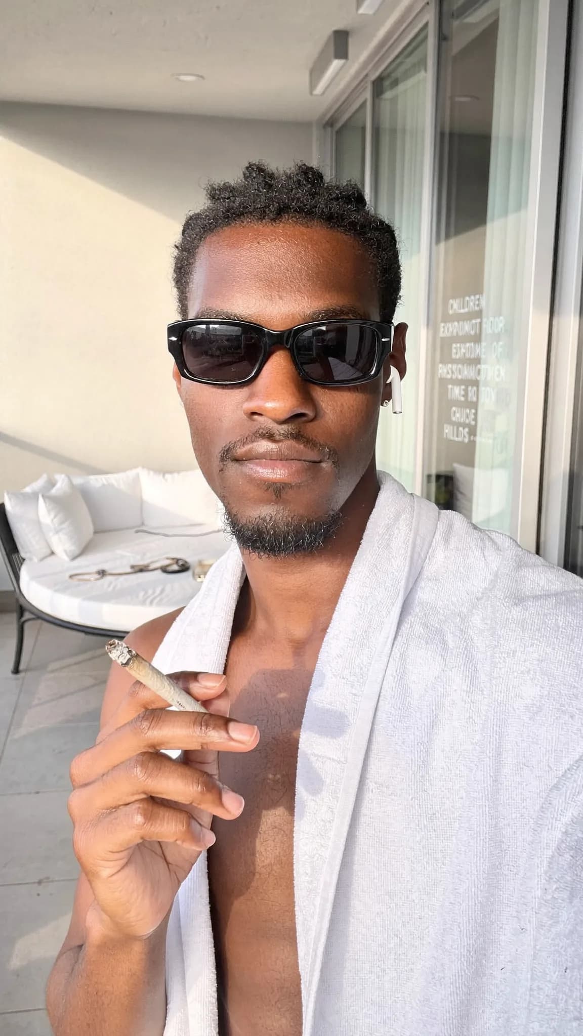 A person wearing a robe is holding a cigarette on a balcony.