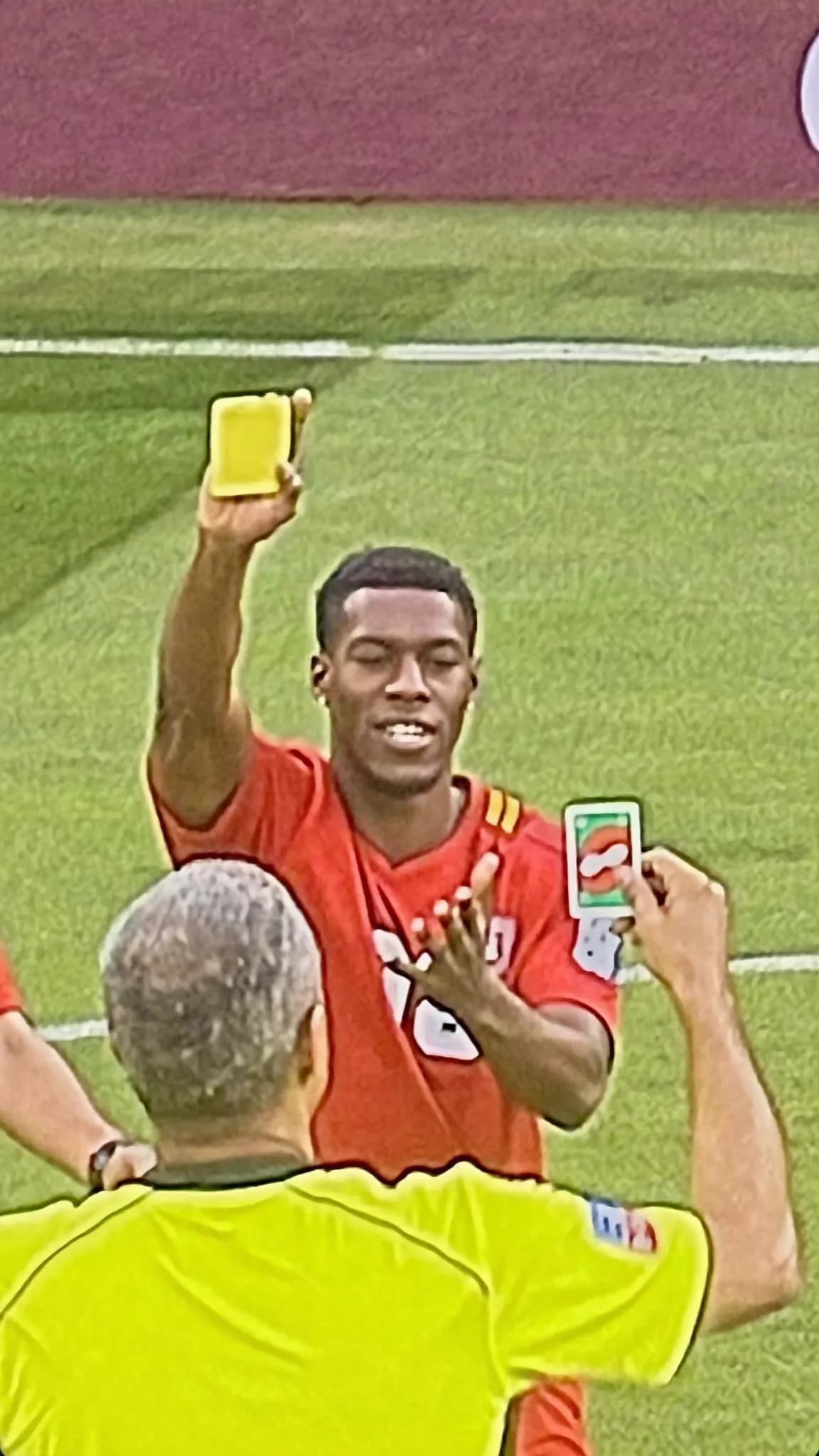 A person in a casual outfit is being photographed outdoors while holding up a yellow card.