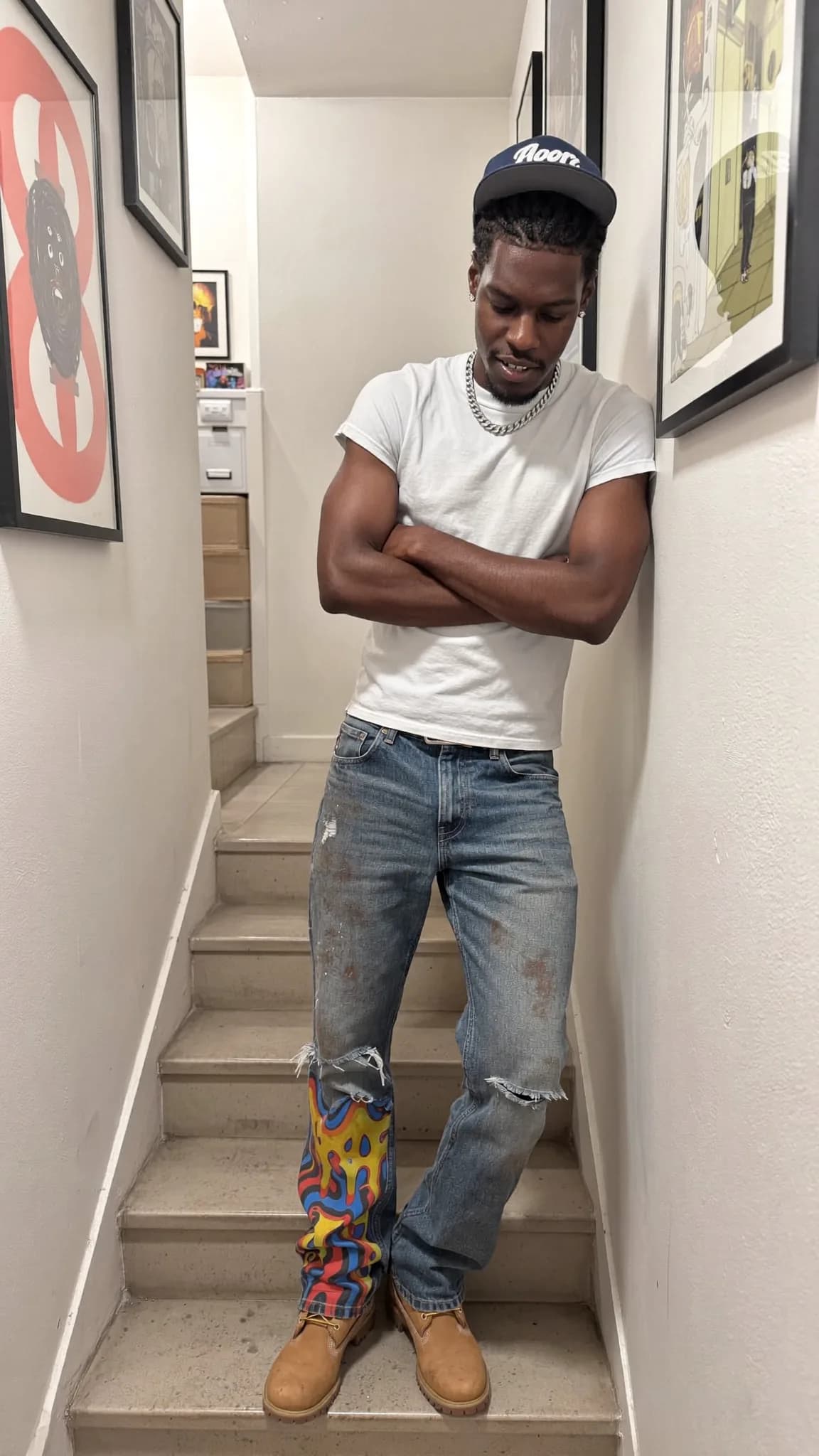 A person stands on stairs wearing casual clothing with a playful expression.