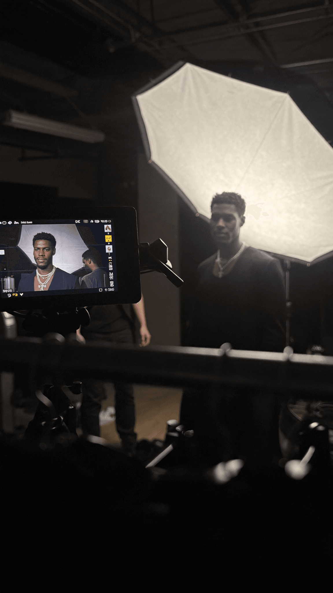 A person is being photographed in a studio with soft lighting and casual attire.