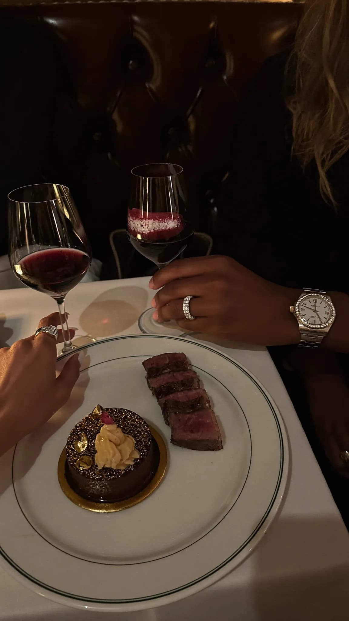 A couple enjoys a romantic dinner with steak and dessert at a restaurant.