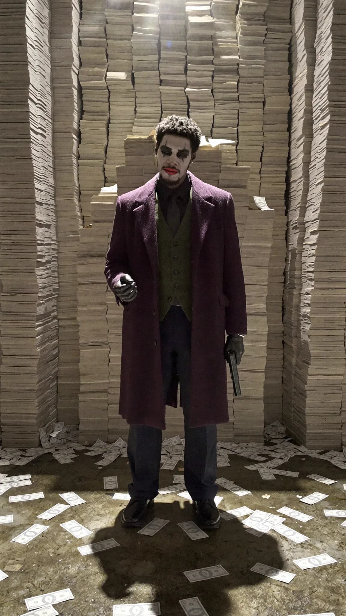 A character dressed as a villain stands amidst stacks of money, holding a gun.