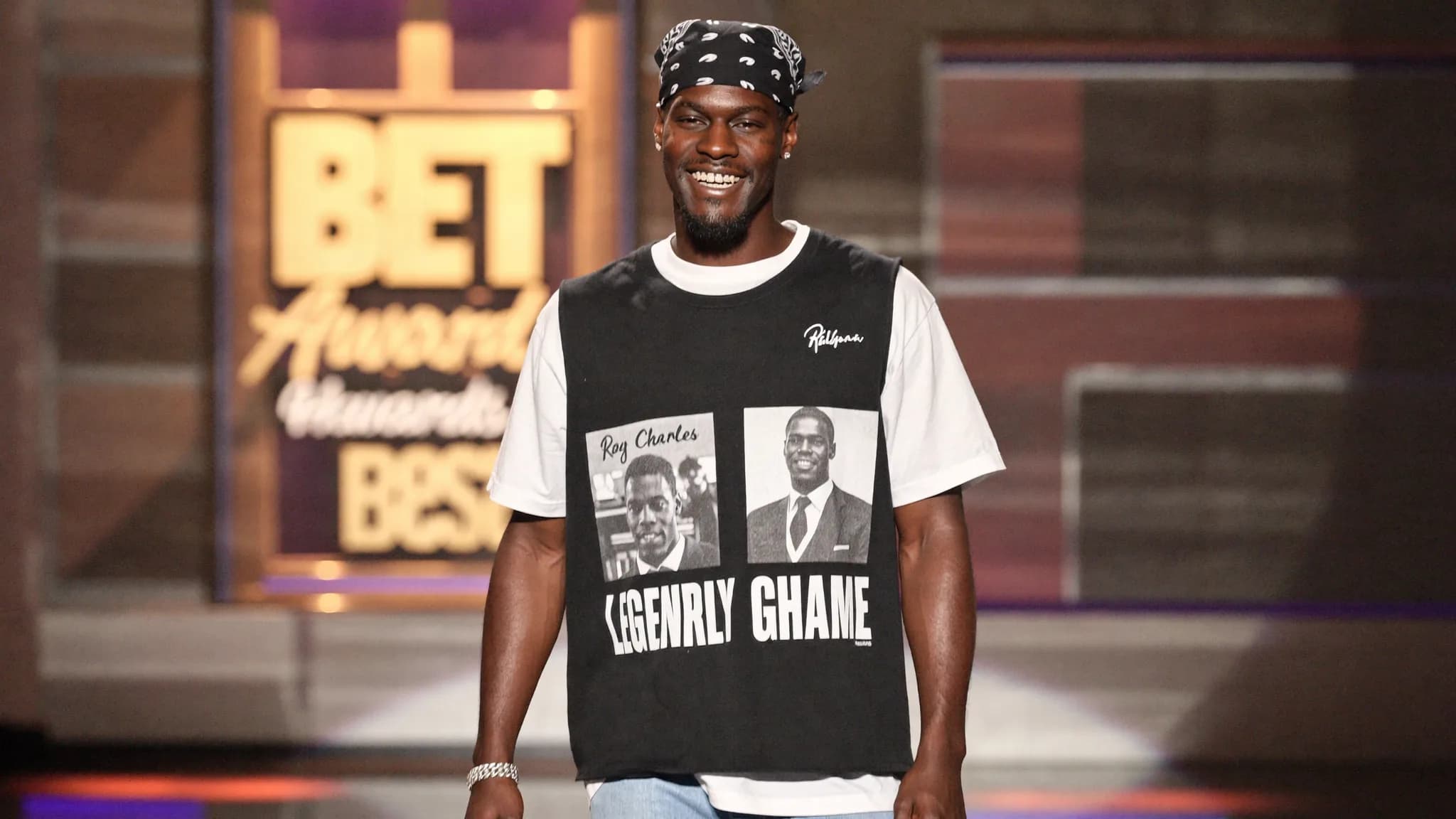 A man wearing a graphic t-shirt and bandana stands on stage at the BET Awards.