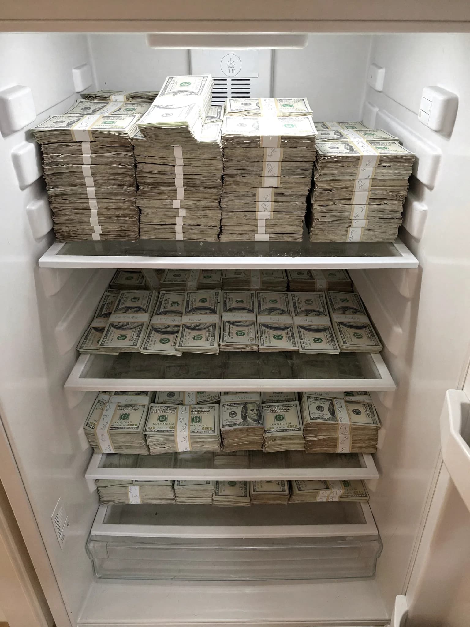 A refrigerator filled with stacks of US dollar bills.