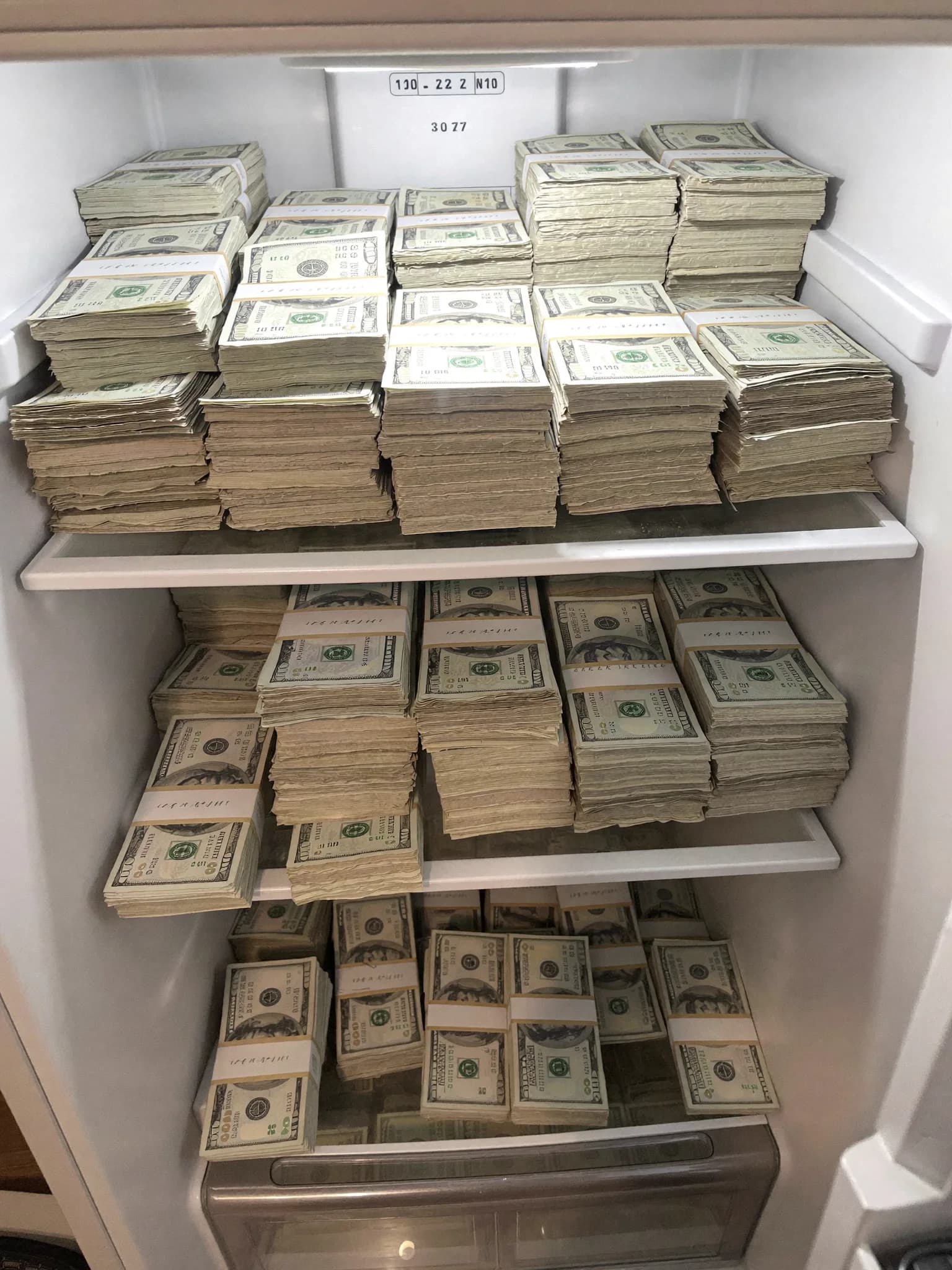 A refrigerator filled with stacks of US dollar bills.