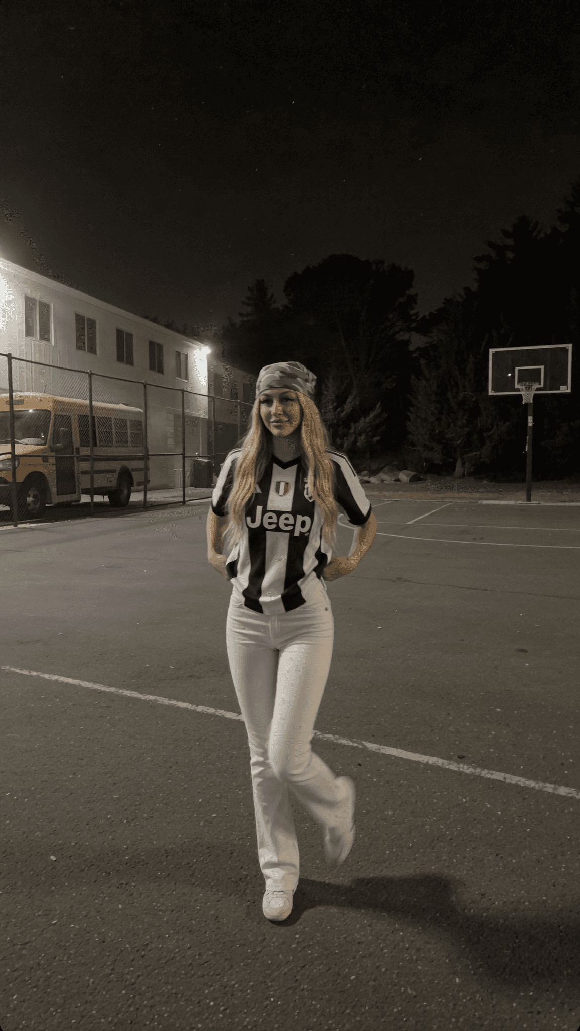 A woman in a Corvette Blondie outfit poses confidently on an outdoor basketball court at night.