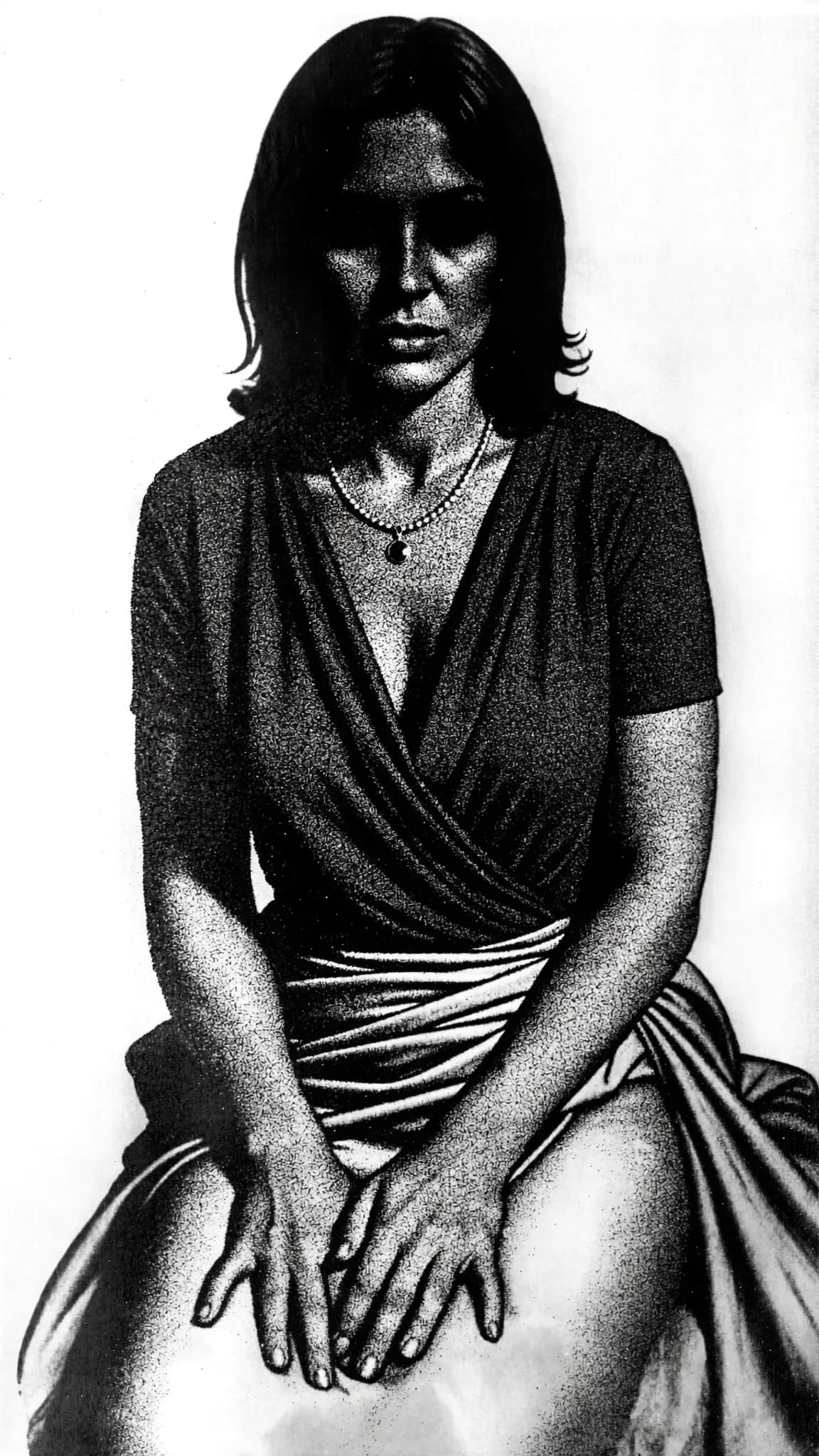 A woman in a dress sits with her hands on her lap, exuding a soft and seductive mood.