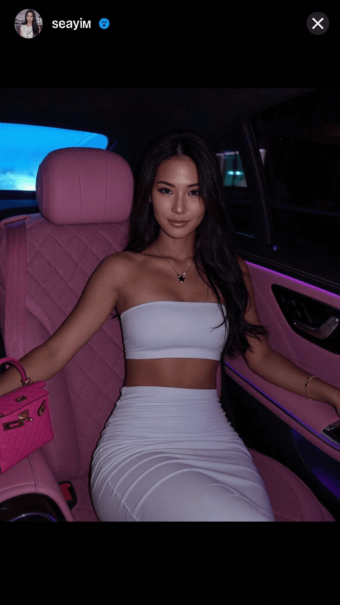 A woman in a dress stands outdoors, exuding confidence and allure.