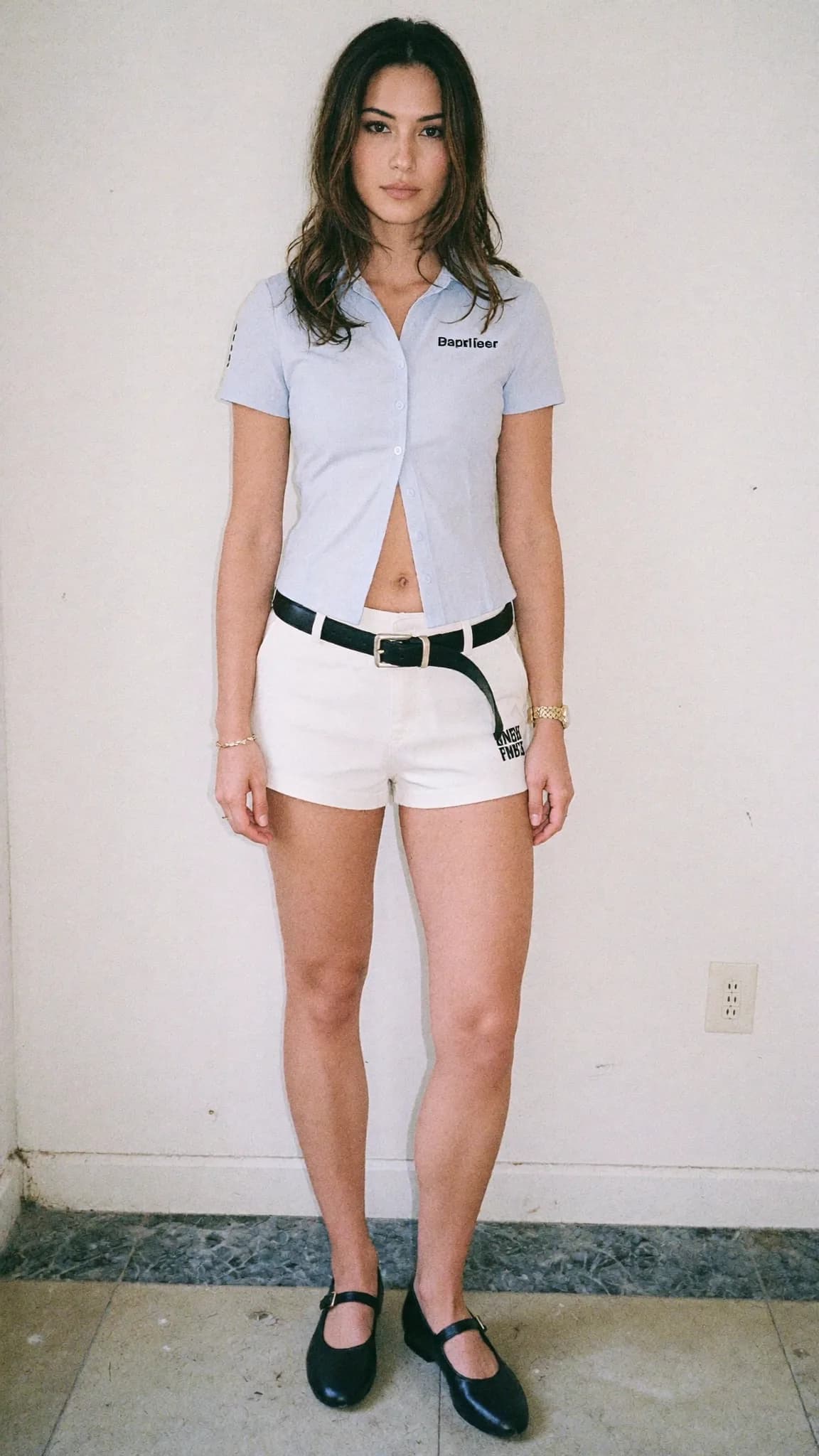A woman stands in a studio wearing casual clothing with a soft and candid mood.