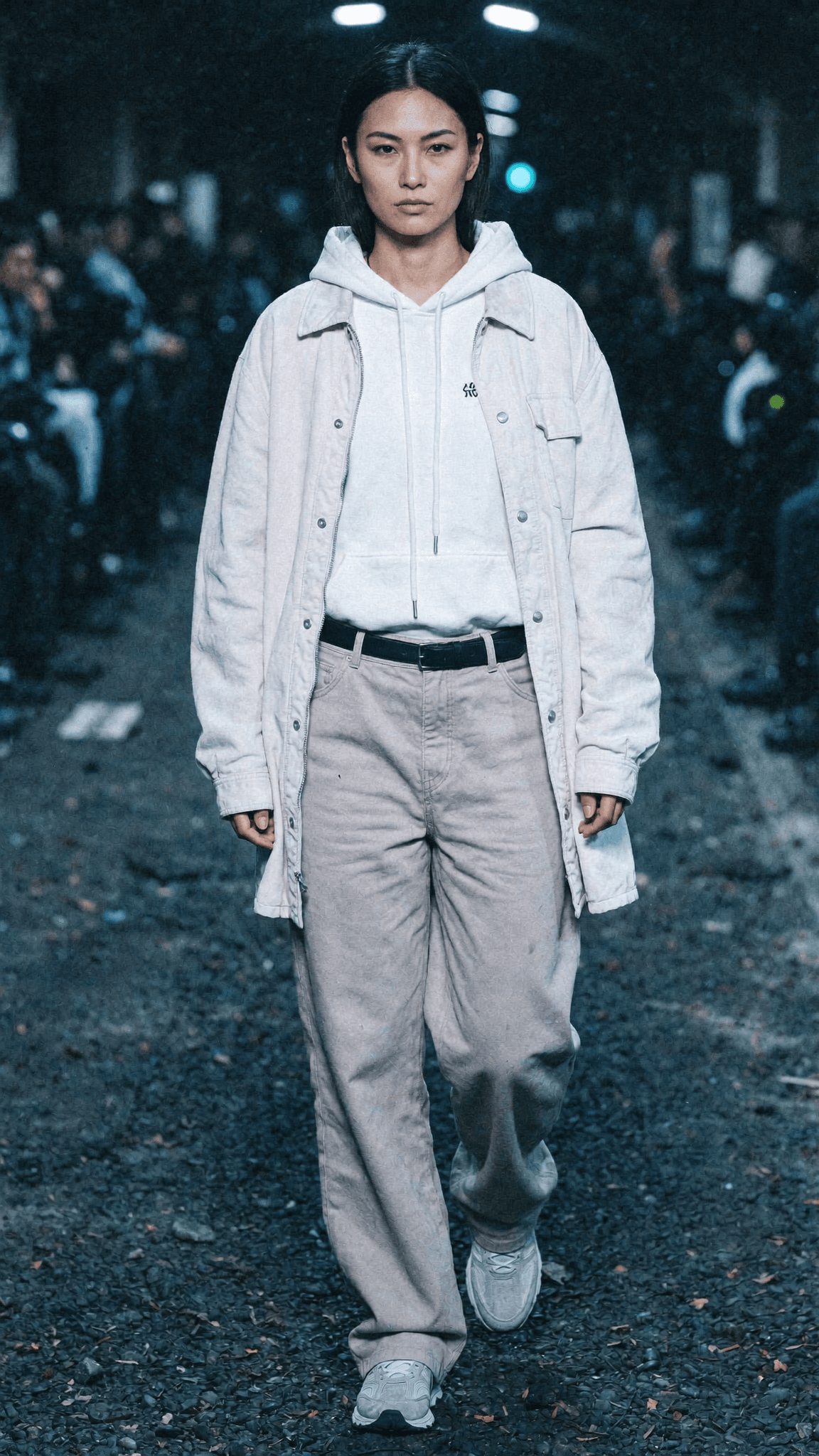 A model walks down a runway wearing casual attire in an outdoor setting.