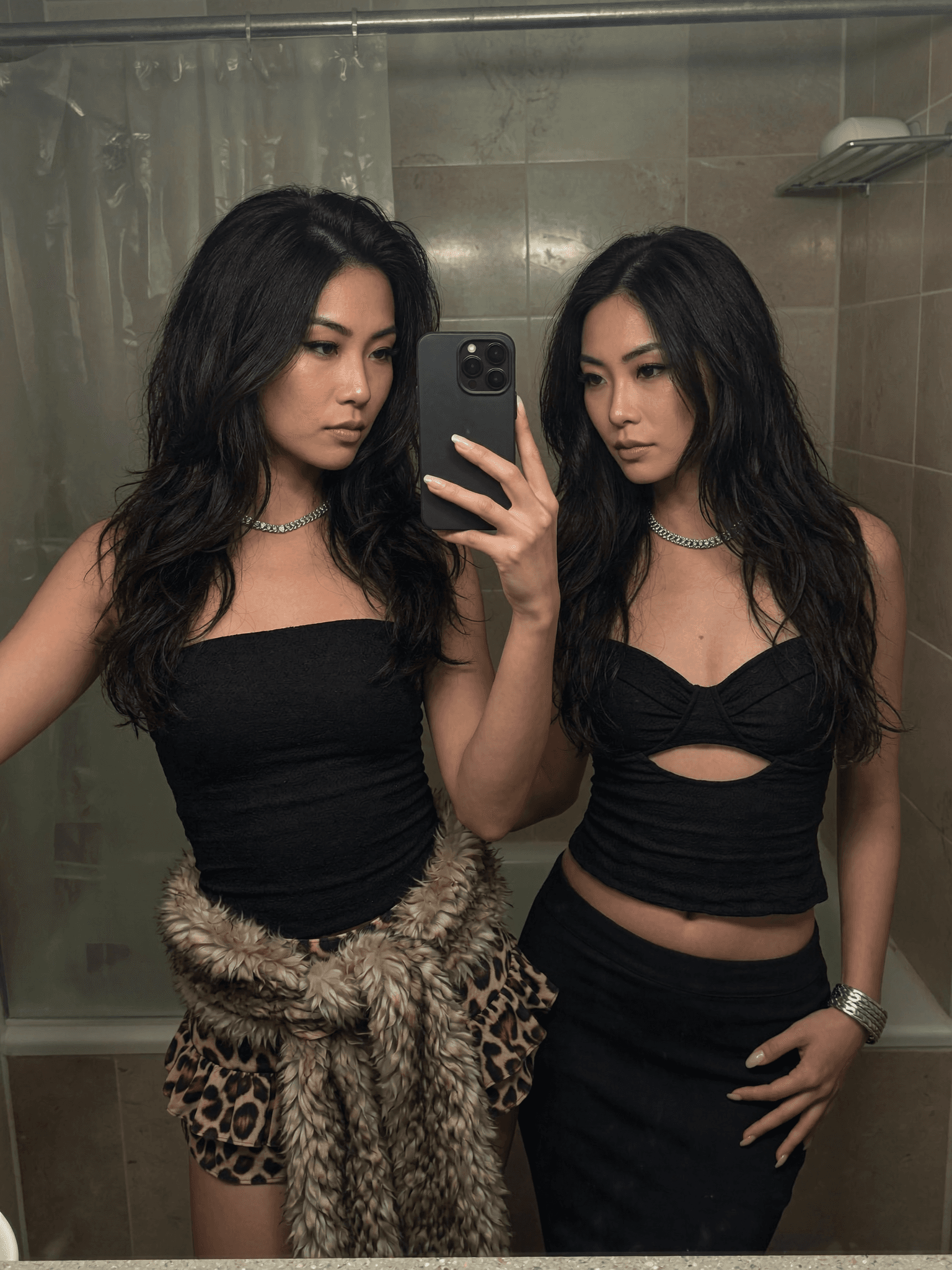 Two individuals in black outfits pose for a mirror selfie, exuding confidence and style.