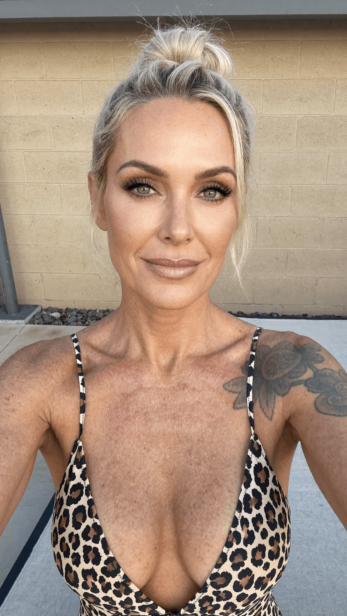 A woman with a leopard print swimsuit poses for the camera outdoors.