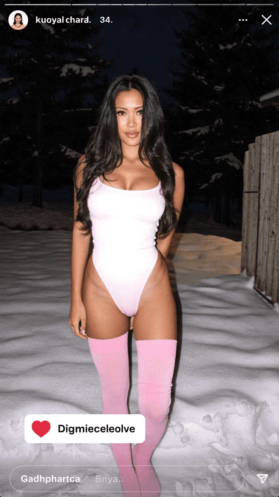 A woman in a swimsuit stands confidently outdoors at night.