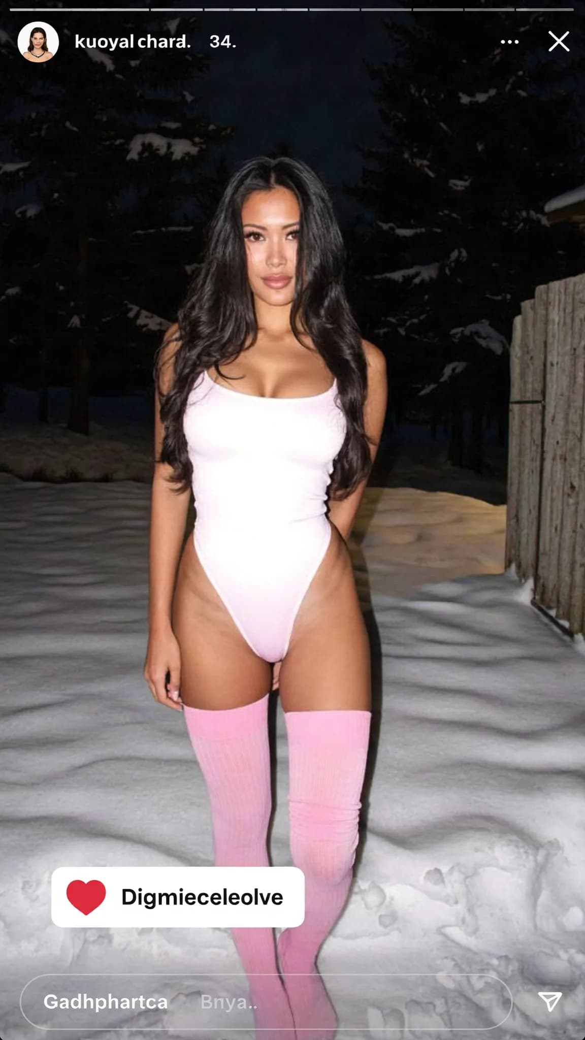 A woman in a swimsuit stands confidently outdoors at night.