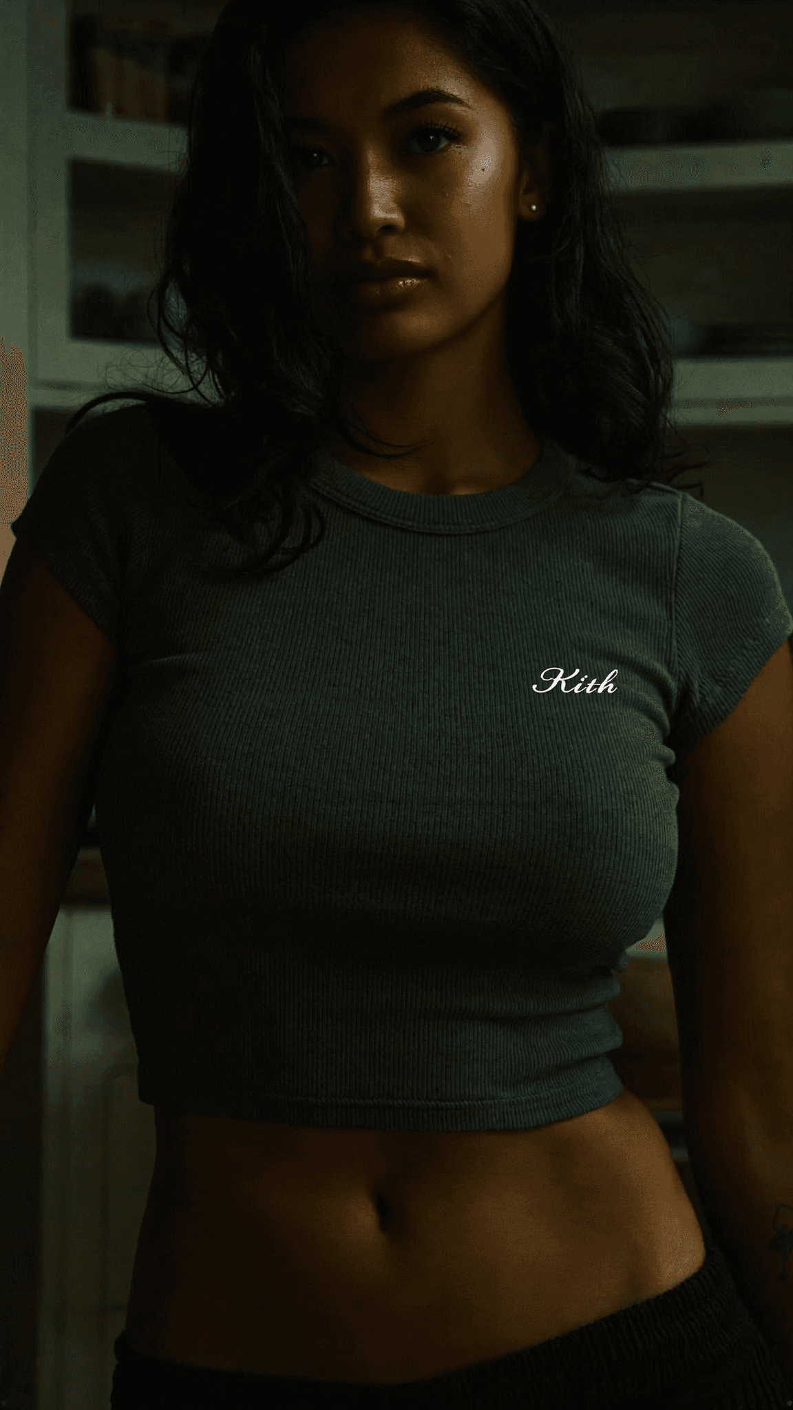 A woman in a casual crop top stands confidently in a kitchen setting.