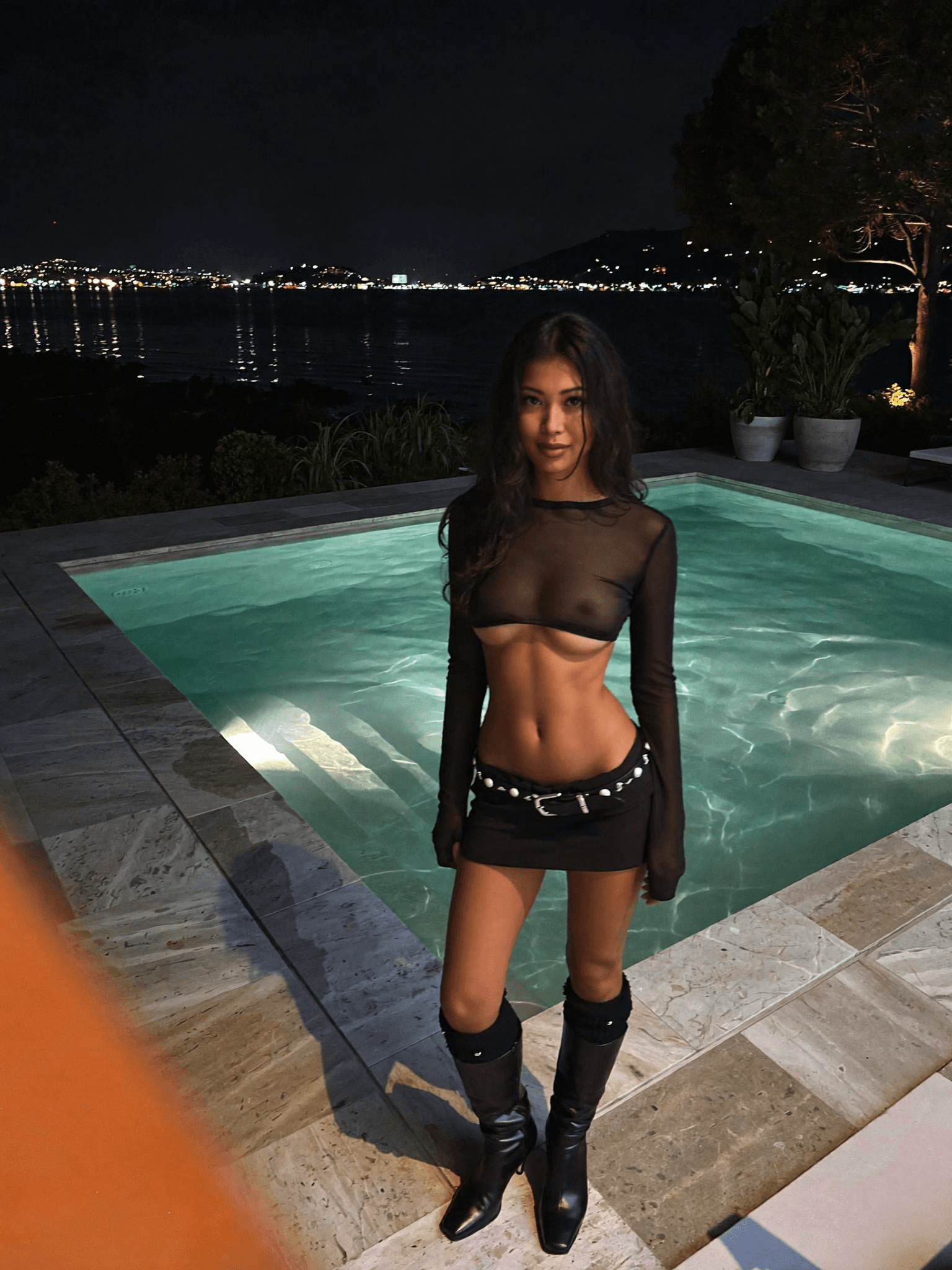 A woman in a dress stands outdoors, exuding confidence and allure.