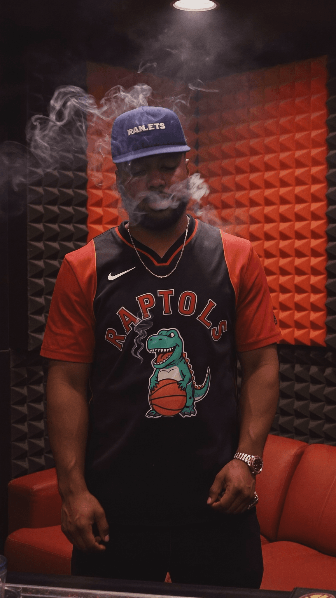A person wearing a Raptors jersey and smoking in a studio setting.