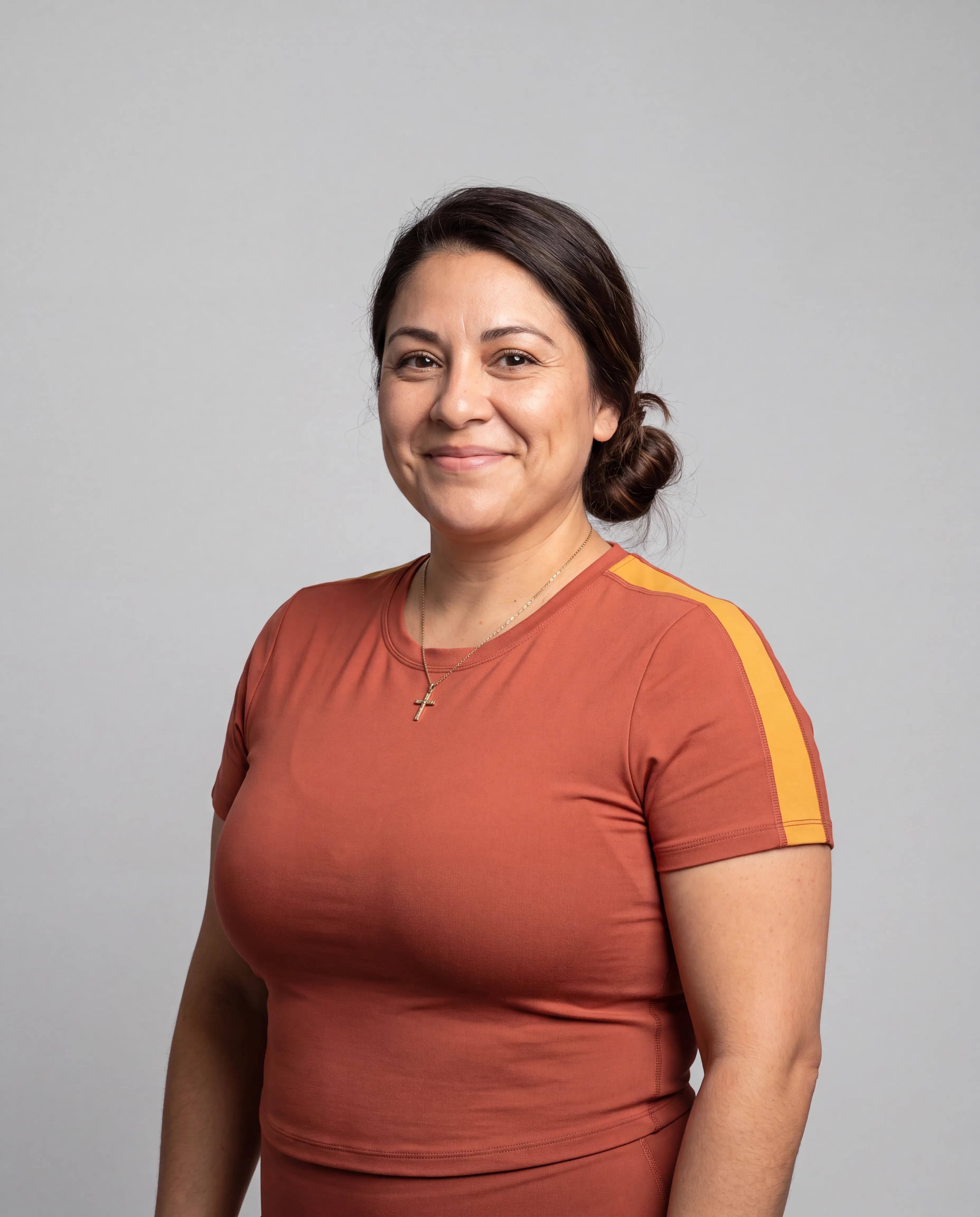 A woman in a casual outfit poses for a portrait against a studio background.