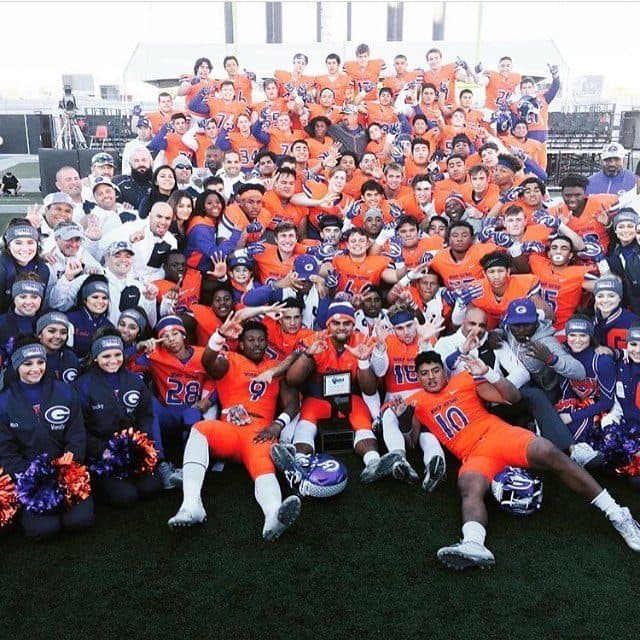 Gaels championship day — the whole program packed around the trophy, four fingers up.