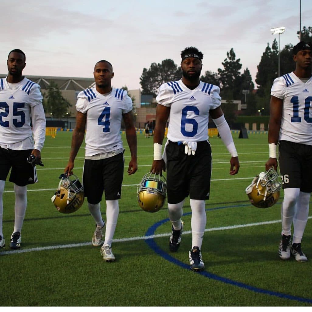 Off the practice field at dusk — gold lids in hand, PICK SIX headband on.